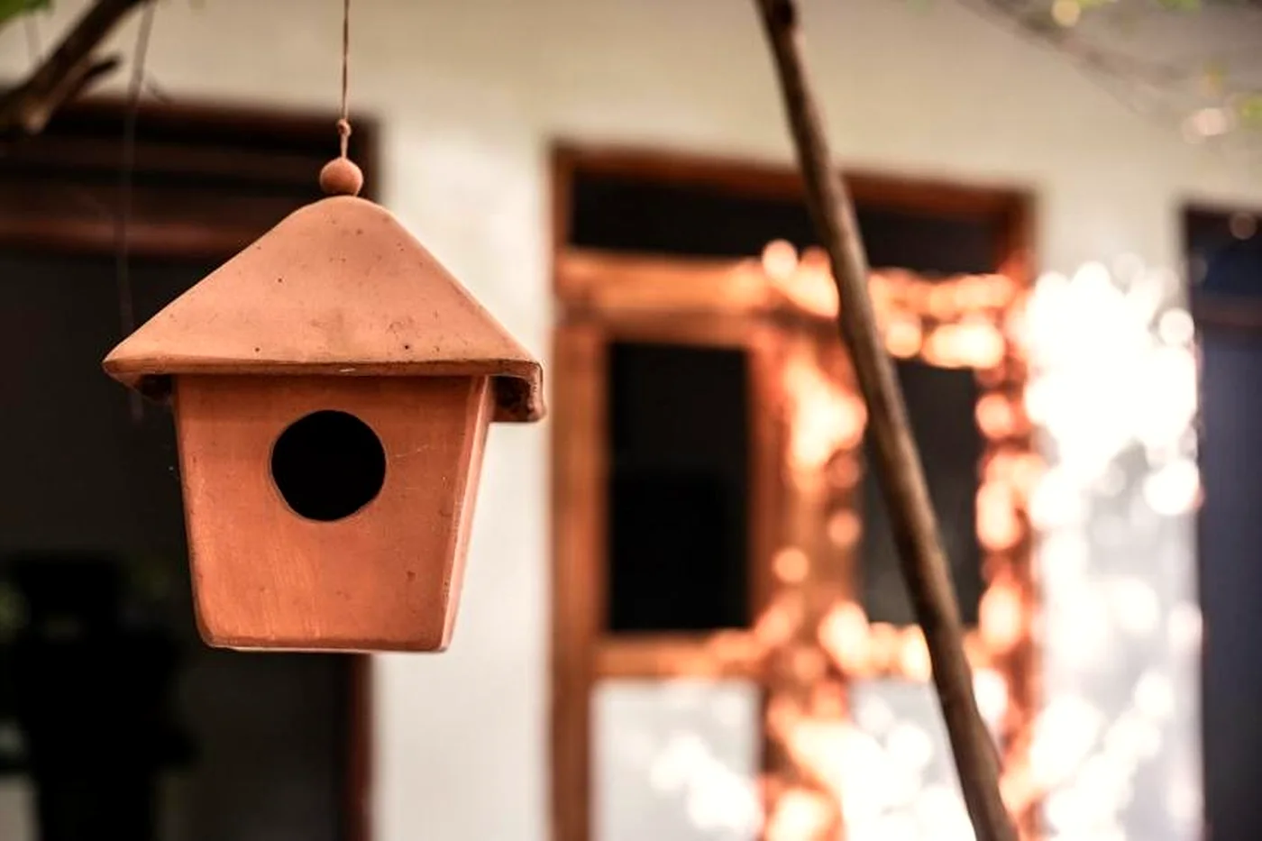 A wooden birdhouse hanging in the garden light