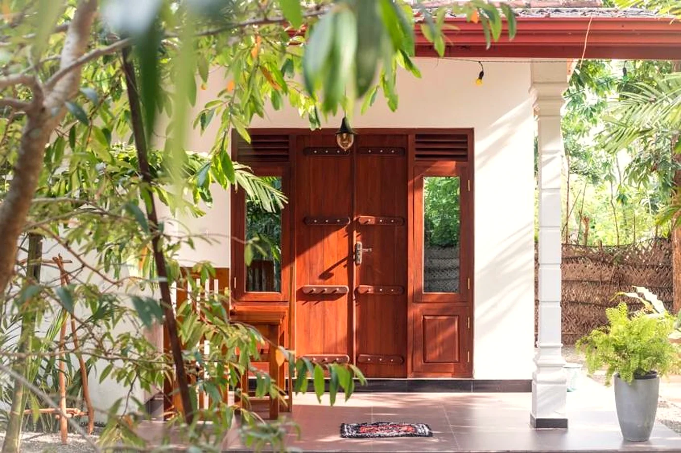 The verandah and wooden doors of AURORA Midigama, framed by trees